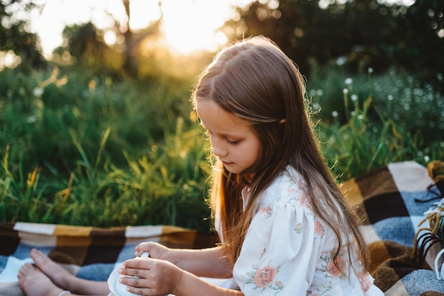 Retrato de uma menina bonitinha no jardim ao pôr do sol