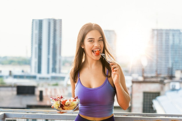 Retrato de uma menina brincalhão feliz comendo salada fresca de sua tigela