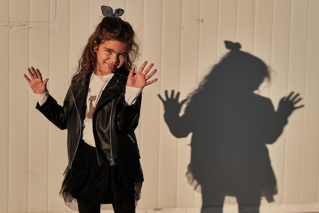 Foto retrato de uma menina brincando com sua sombra ao pôr do sol.