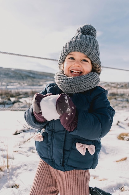 Retrato de uma menina brincando na neve pela primeira vez