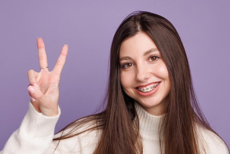 Foto retrato de uma menina com aparelhos ortopédicos mulher feliz com aparelho ortopédico mostra sinal ok