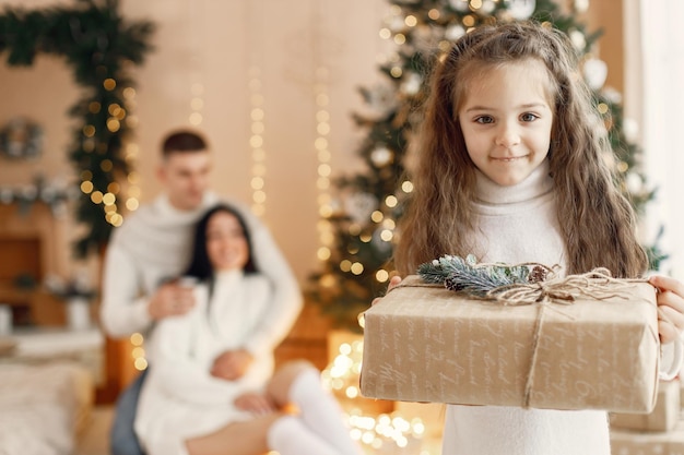 Retrato de uma menina com caixa de presente e seus pais atrás