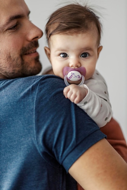 Foto retrato de uma menina com chupeta olhando para a câmera com seu pai