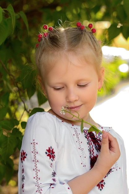 Retrato de uma menina com flores em uma camisa bordada ucraniana Garota cheira uma flor