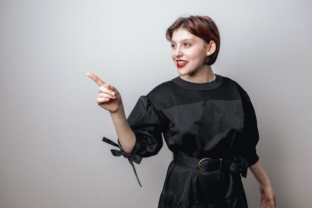 Retrato de uma menina com lábios vermelhos em um elegante vestido preto sobre um fundo claro