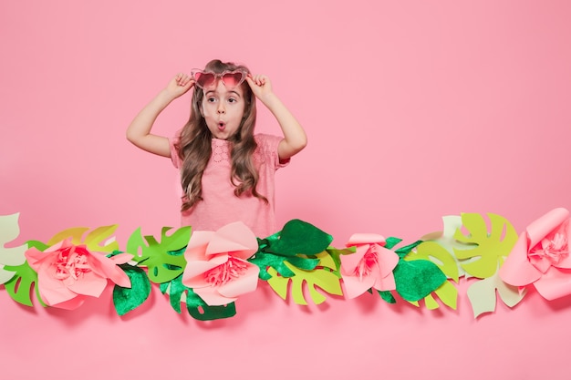 Retrato de uma menina com óculos de sol em uma parede rosa