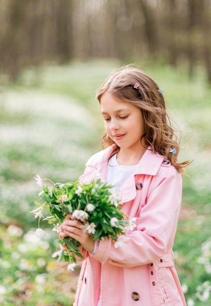 Retrato de uma menina com prímulas em uma floresta de primavera