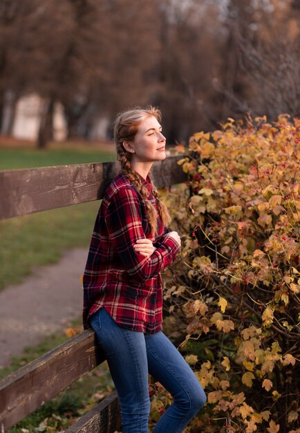 Retrato de uma menina com tranças, ao lado de uma cerca de madeira