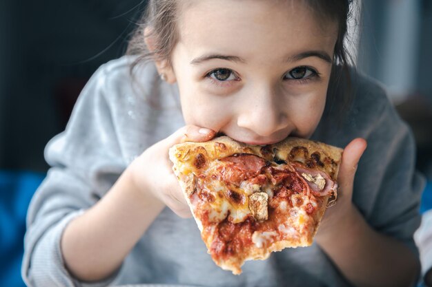 Retrato de uma menina com um apetitoso pedaço de pizza