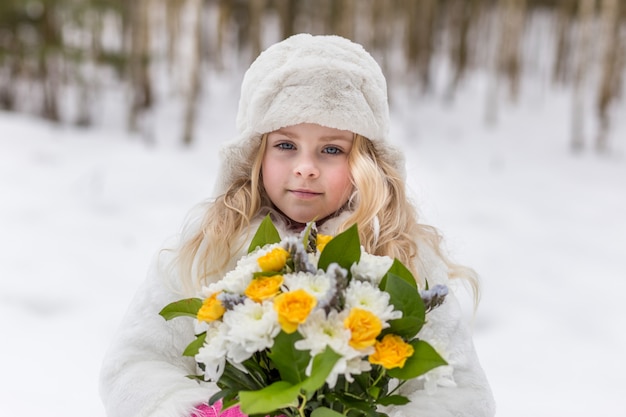 Retrato de uma menina com um buquê de flores na floresta no inverno