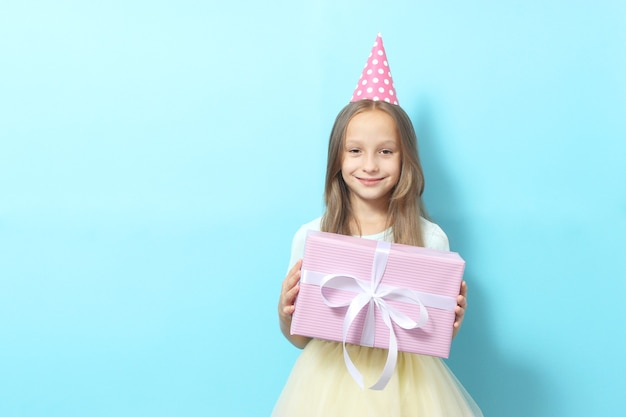 Retrato de uma menina com um chapéu festivo e um presente nas mãos