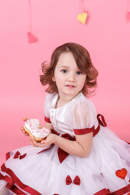 Retrato de uma menina com um donut nas mãos rosa