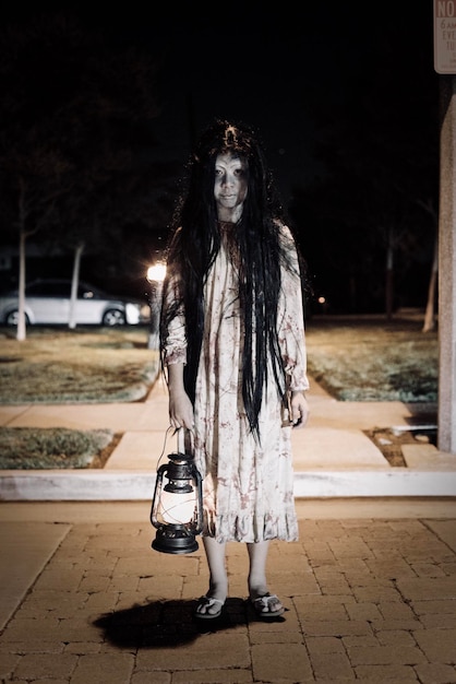 Foto retrato de uma menina com um traje assustador de pé na rua à noite