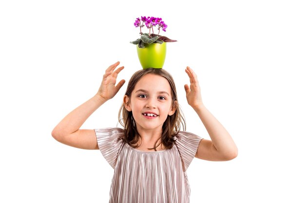 Foto retrato de uma menina com um vaso de flores na cabeça de pé contra um fundo branco