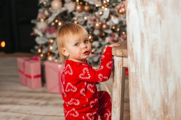 Retrato de uma menina com uma fantasia de Natal em casa perto da cadeira