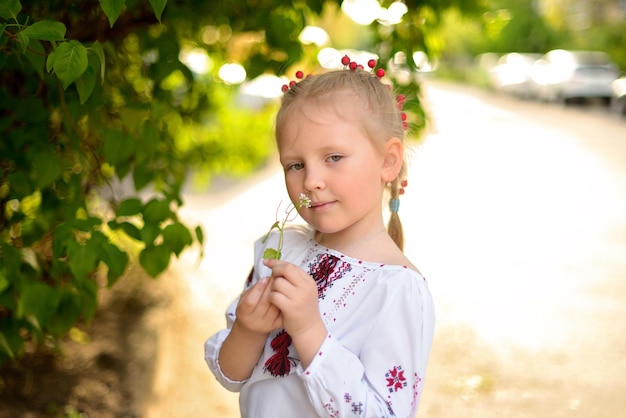 Retrato de uma menina com uma flor em uma camisa bordada ucraniana Garota cheira uma flor