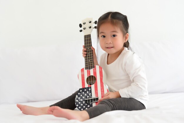 Retrato de uma menina com uma guitarra na cama em casa