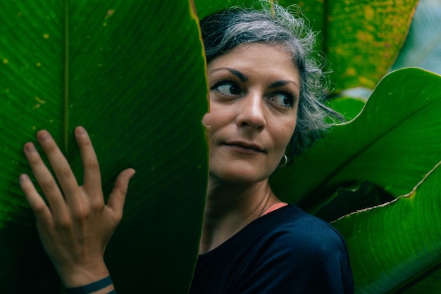 Foto retrato de uma menina contra o fundo de grandes folhas tropicais