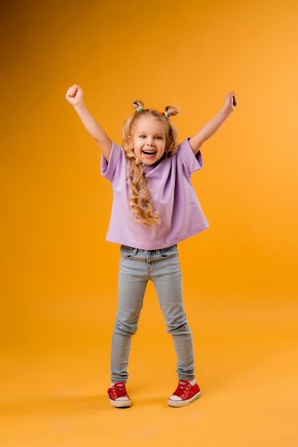 Foto retrato de uma menina criança feliz isolar em um espaço amarelo, espaço para texto