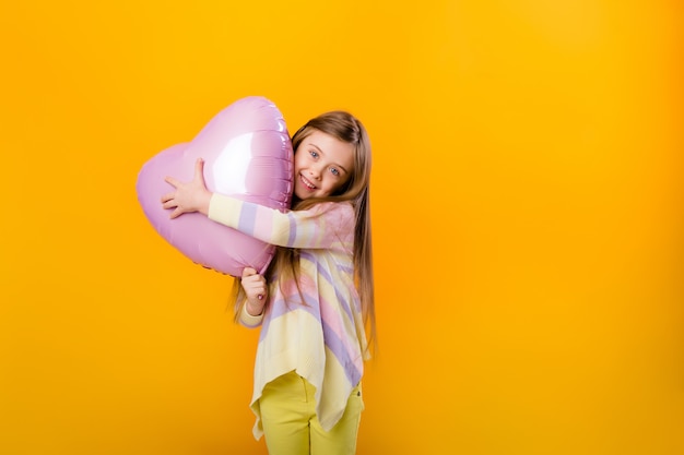 Retrato de uma menina criança feliz sorrindo segurando um balão rosa em forma de coração