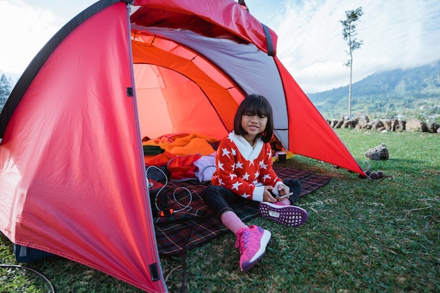 Retrato de uma menina curtindo o acampamento com a bela paisagem da colina