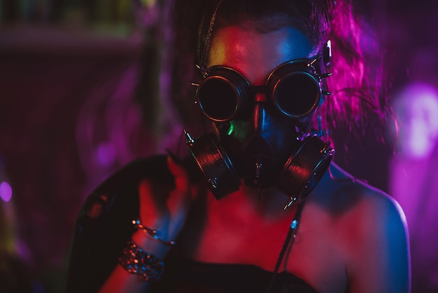 Retrato de uma menina cyberpunk com uma máscara de gás e óculos no estilo do pós-apocalipse. Estilo Steampunk com luz neon