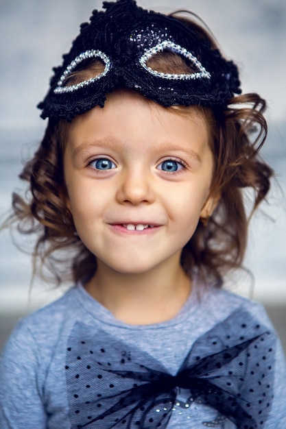 Retrato de uma menina de 2 anos com uma máscara preta e um grande laço