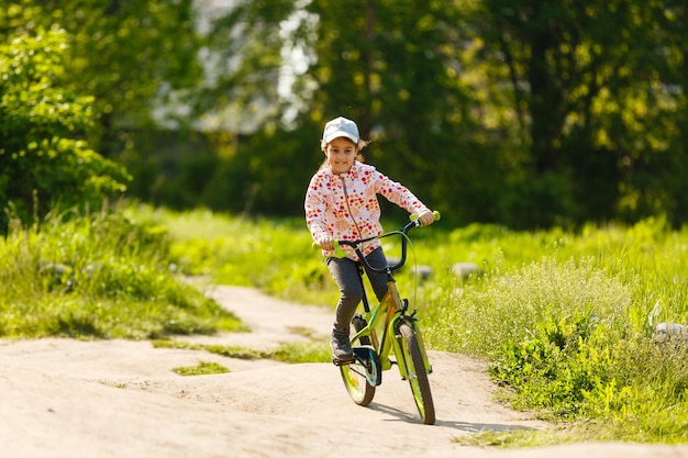 Retrato de uma menina de bicicleta em um parque de verão ao ar livre