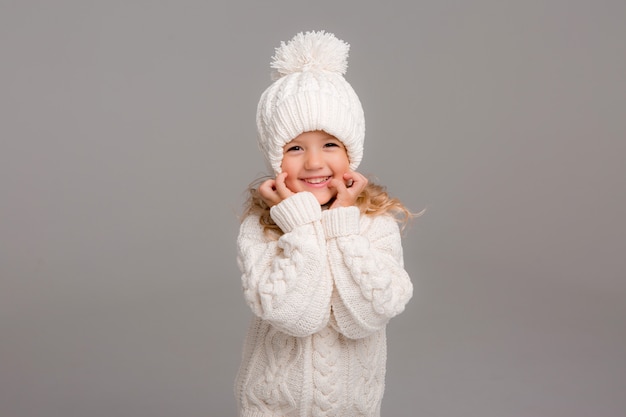 Retrato de uma menina de cabelos cacheados em um chapéu branco de malha de inverno