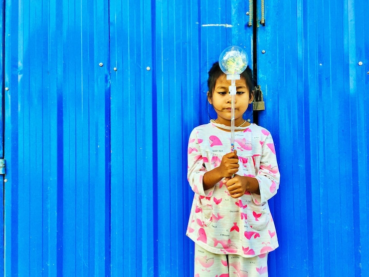 Foto retrato de uma menina de pé contra a parede azul