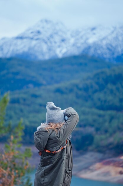 Foto retrato de uma menina de pé e tirando uma foto de montanhas na natureza