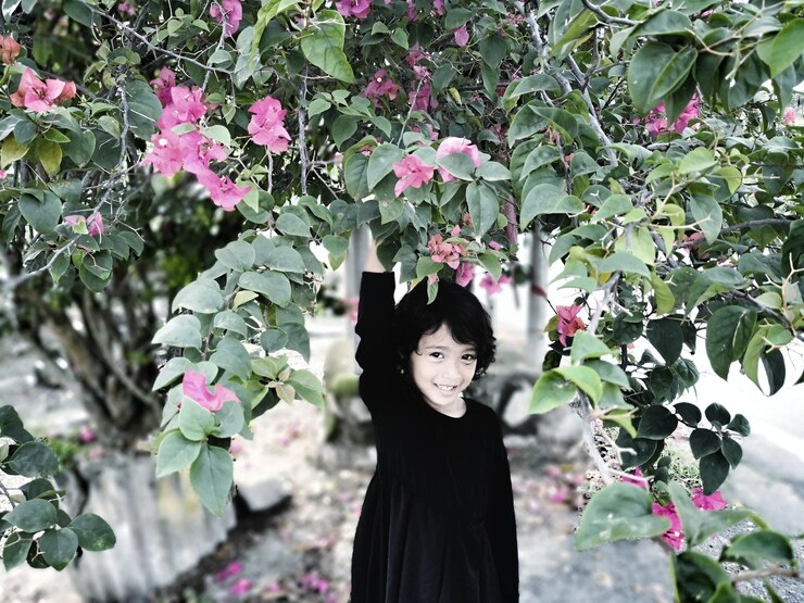 Foto retrato de uma menina de pé sob plantas com flores