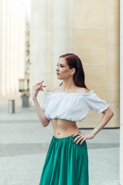 Retrato de uma menina de trinta anos com roupas de verão no contexto de um edifício moderno.