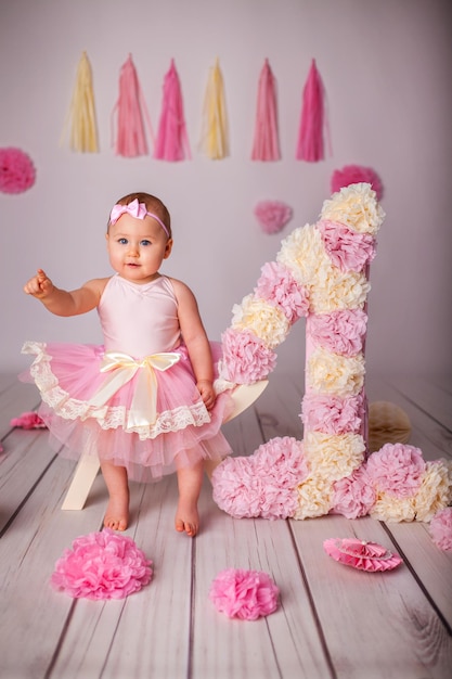 Foto retrato de uma menina de um ano com festa de papel deko e grande número um