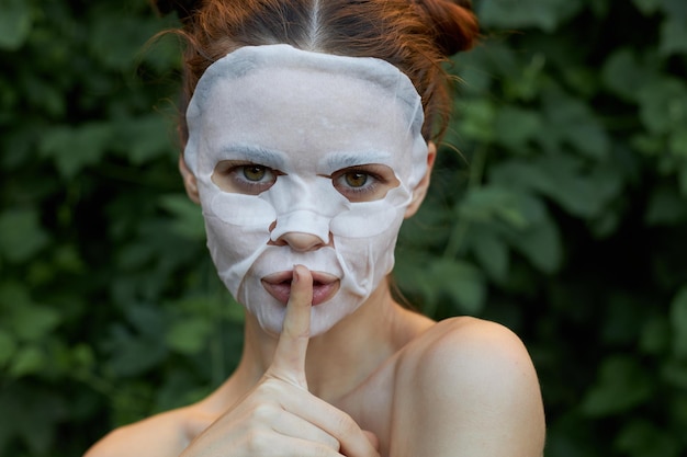 Retrato de uma menina dedo perto dos lábios pedido de silêncio máscara branca cosmetologia close-up