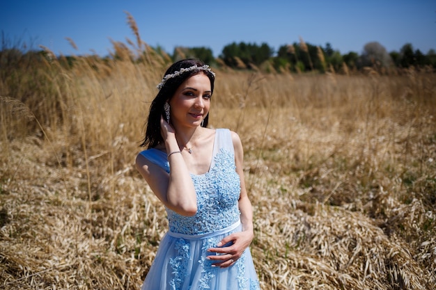 Retrato de uma menina delicada em um vestido azul longo com ervilhas secas com um sorriso no rosto em um dia quente e ensolarado de verão