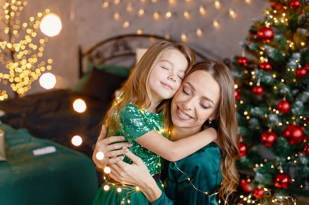 Retrato de uma menina e sua mãe abraçando na atmosfera de Natal