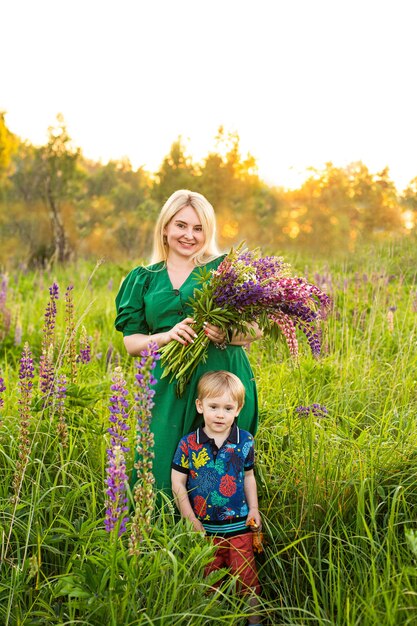 Retrato de uma menina e um filho em um campo florido ao sol ao pôr do sol