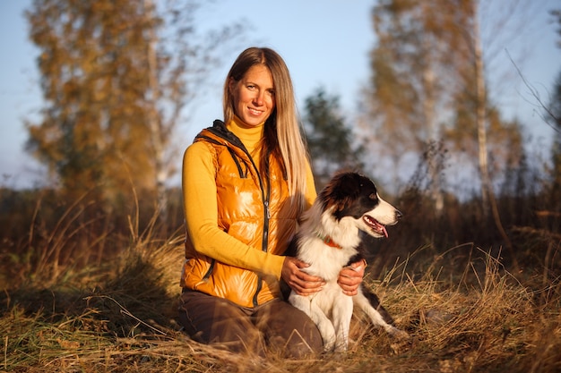 Retrato de uma menina em amarelo e border collie em um fundo de natureza.