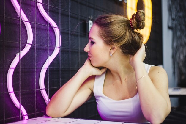 Retrato de uma menina em um café da cidade, iluminação neon e estilo da juventude