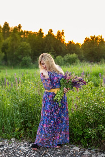 Retrato de uma menina em um campo florido ao sol ao pôr do sol
