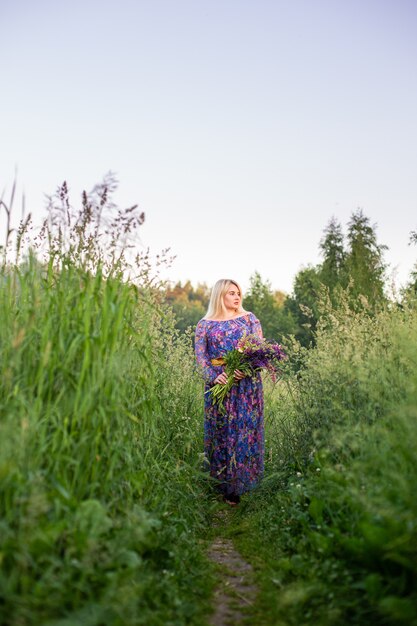 Retrato de uma menina em um campo florido ao sol ao pôr do sol