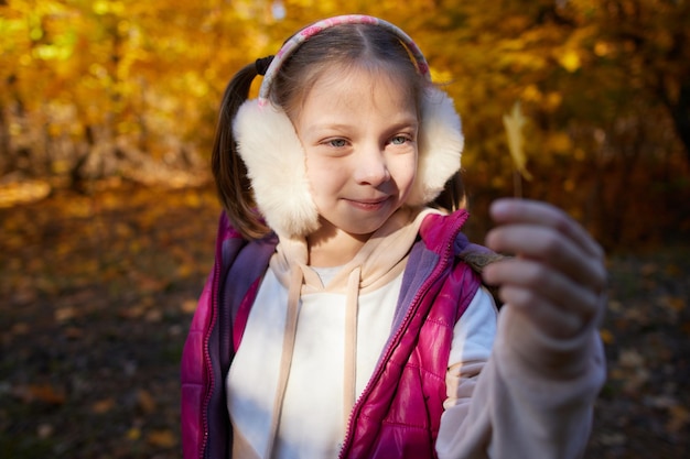 Retrato de uma menina em um parque de outono em um dia ensolarado