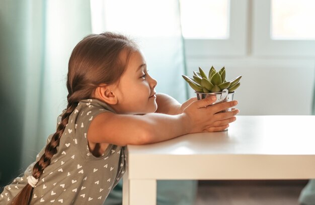 Retrato de uma menina em um quarto com uma flor suculenta