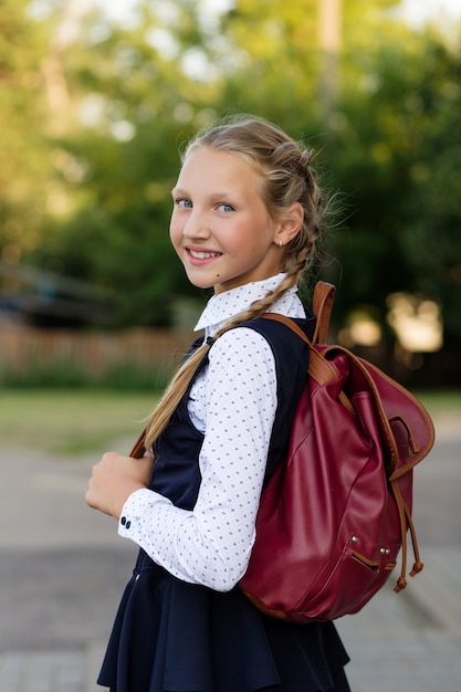 Foto retrato de uma menina em um uniforme escolar e uma mochila