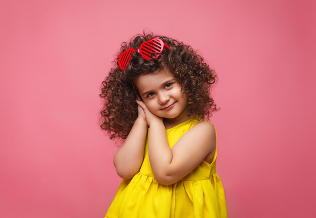 Foto retrato de uma menina em um vestido amarelo bonito atraente menina alegre alegre menina isolada fundo rosa