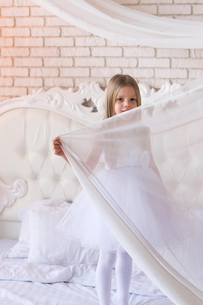 Retrato de uma menina em um vestido branco. A garota cobre o rosto com um pano branco.