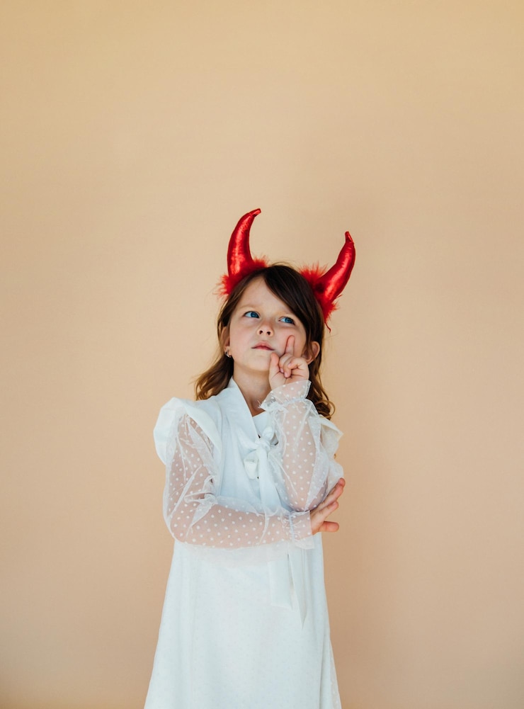 Foto retrato de uma menina em um vestido branco com chifres de diabo traje de halloween expressão facial angelical o conceito de duas personalidades diferentes no personagem