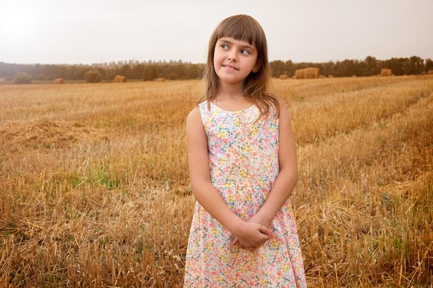 Retrato de uma menina em um vestido de verão em um campo em um dia ensolarado crianças na natureza