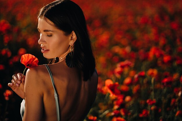 Retrato de uma menina em um vestido em um campo de papoulas ao pôr do sol